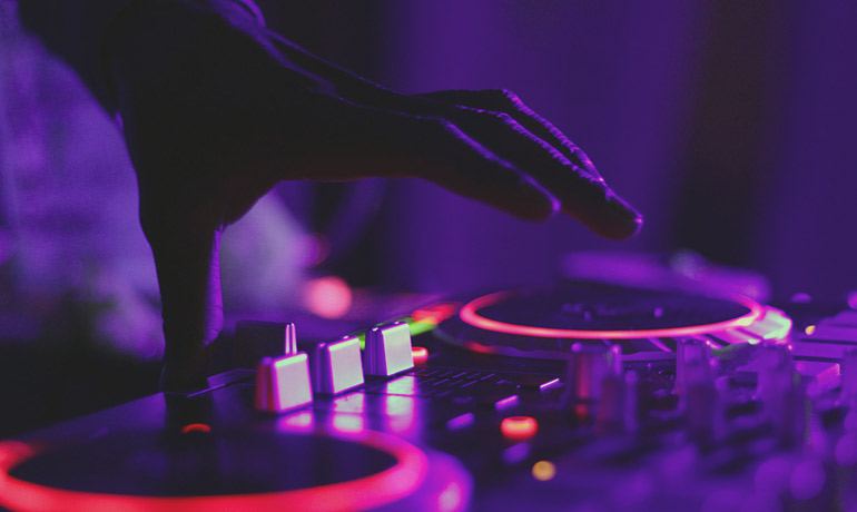 DJ hand on a mixer under purple light