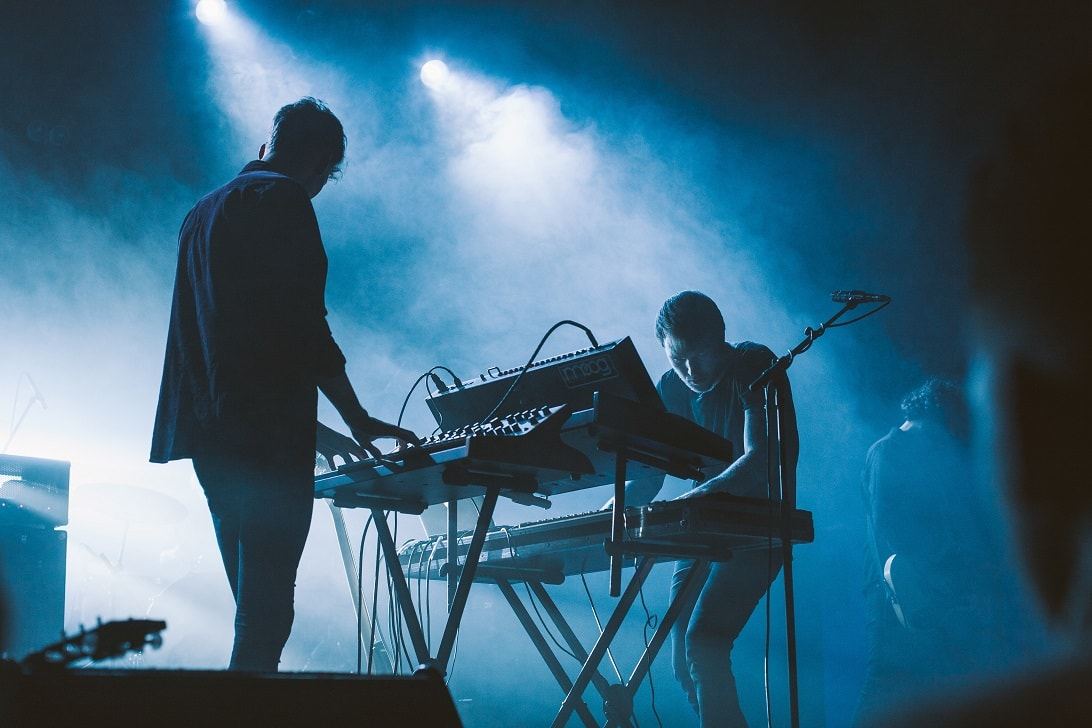 Performers on a blue-lit stage with keyboards